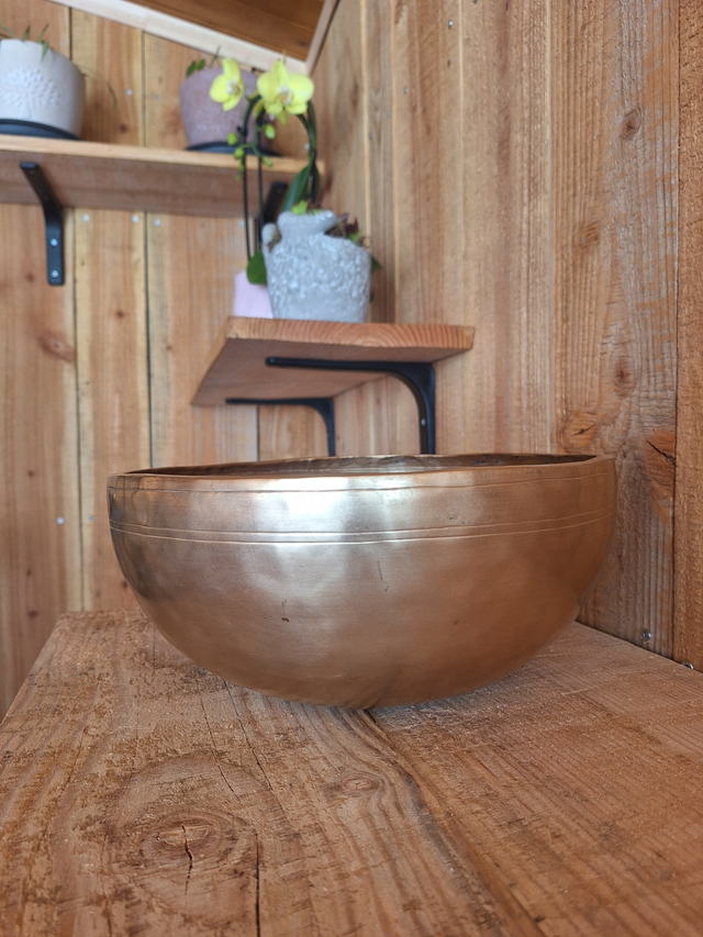 Gros plan sur un grand bol chantant tibétain posé sur une planche de bois brut