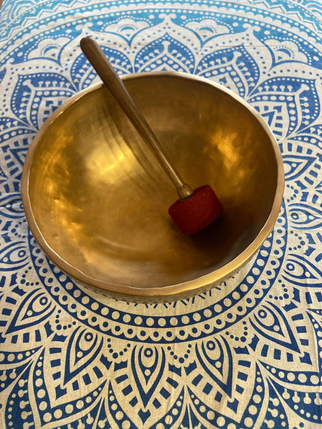 Bol chantant tibétain vu du dessus, un maillet rouge posé à l'intérieur, sur un tissu mandala bleu