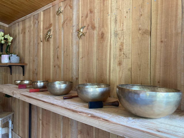 Rangée de bols chantants tibétains de tailles croissantes posés sur une longue étagère en bois
