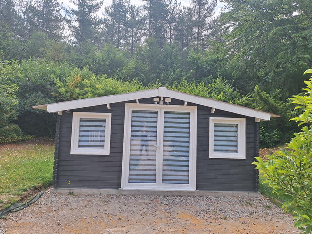Façade du chalet du bien-être avec sa porte vitrée, entouré de verdure