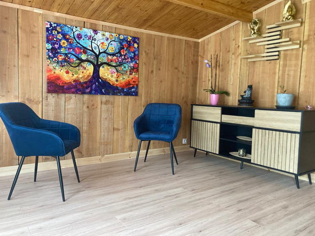 Coin accueil du chalet : deux fauteuils en velours bleu, un grand tableau arbre de vie et un buffet en bois